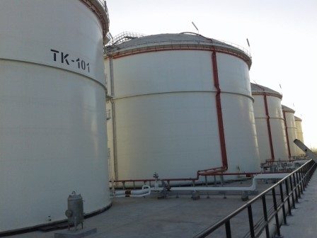 Large white storage tanks, one marked TK-101, inside their bund.