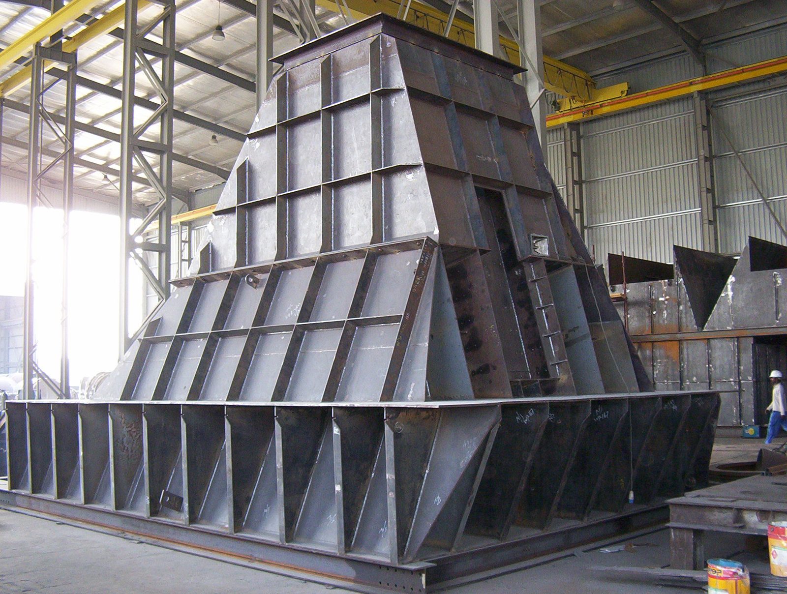 A large steel hopper for a bag filter, under fabrication in a workshop bay.