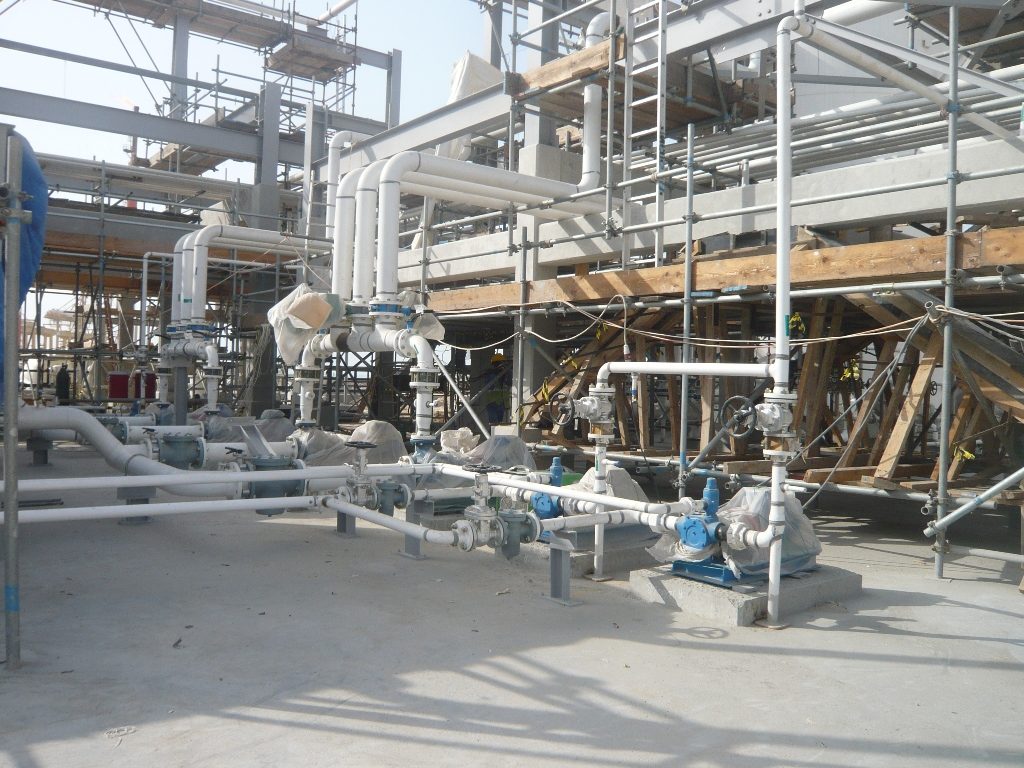 Pipework and pumps being installed beneath scaffolding.